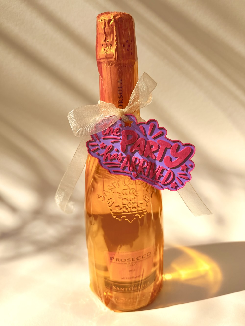 Flaschenanhänger "The Party has arrived" in Lila-Pink an einer Proseccoflasche