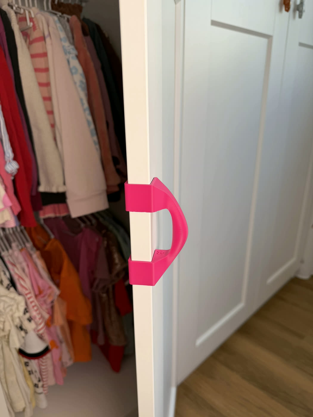 Mitwachsender Griff in Pink an einer geöffneten Kleiderschranktür im Kinderzimmer
